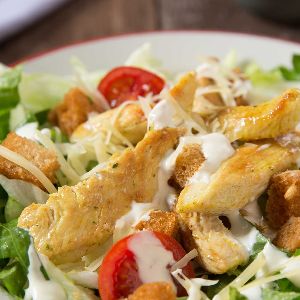 una gran fuente de lechuga, tomate, pollo, tropezones de pan tostado, queso y una exquisita salsa especial a base de anchoas, mayonesa y el secreto de la Proa